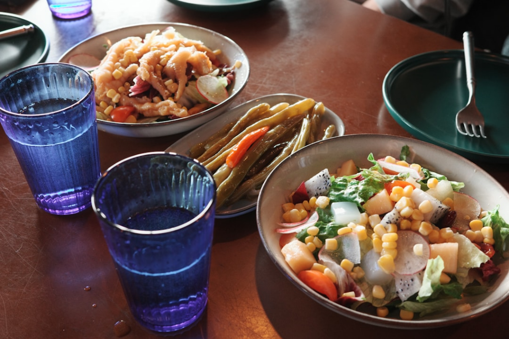 a wooden table topped with bowls of food by Young Kane